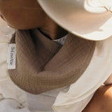 Close-up of a baby wearing a brown muslin bandana bib by Soloveable.