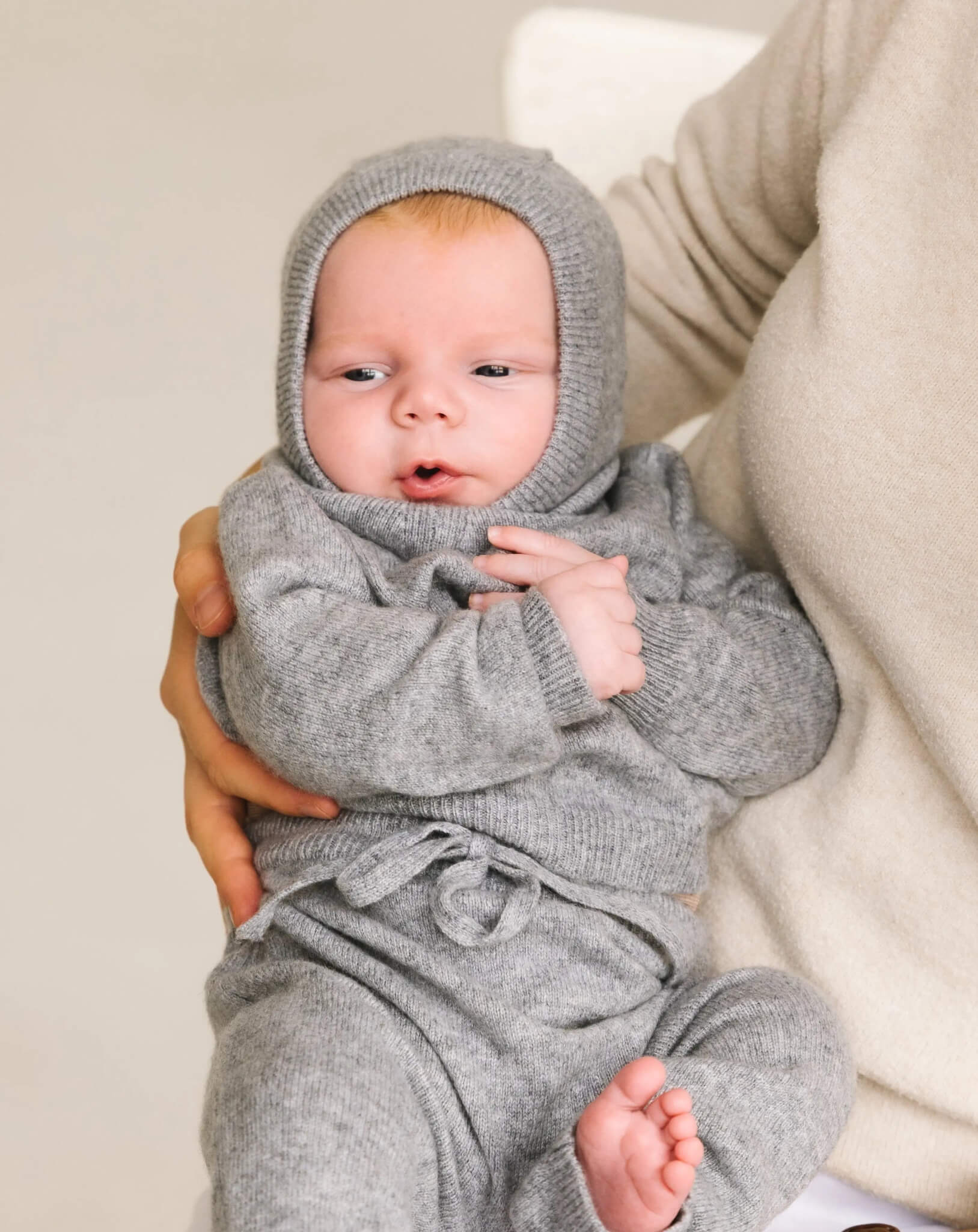 Baby wearing soft heather grey cashmere balaclava, warm knitted hood for infants.