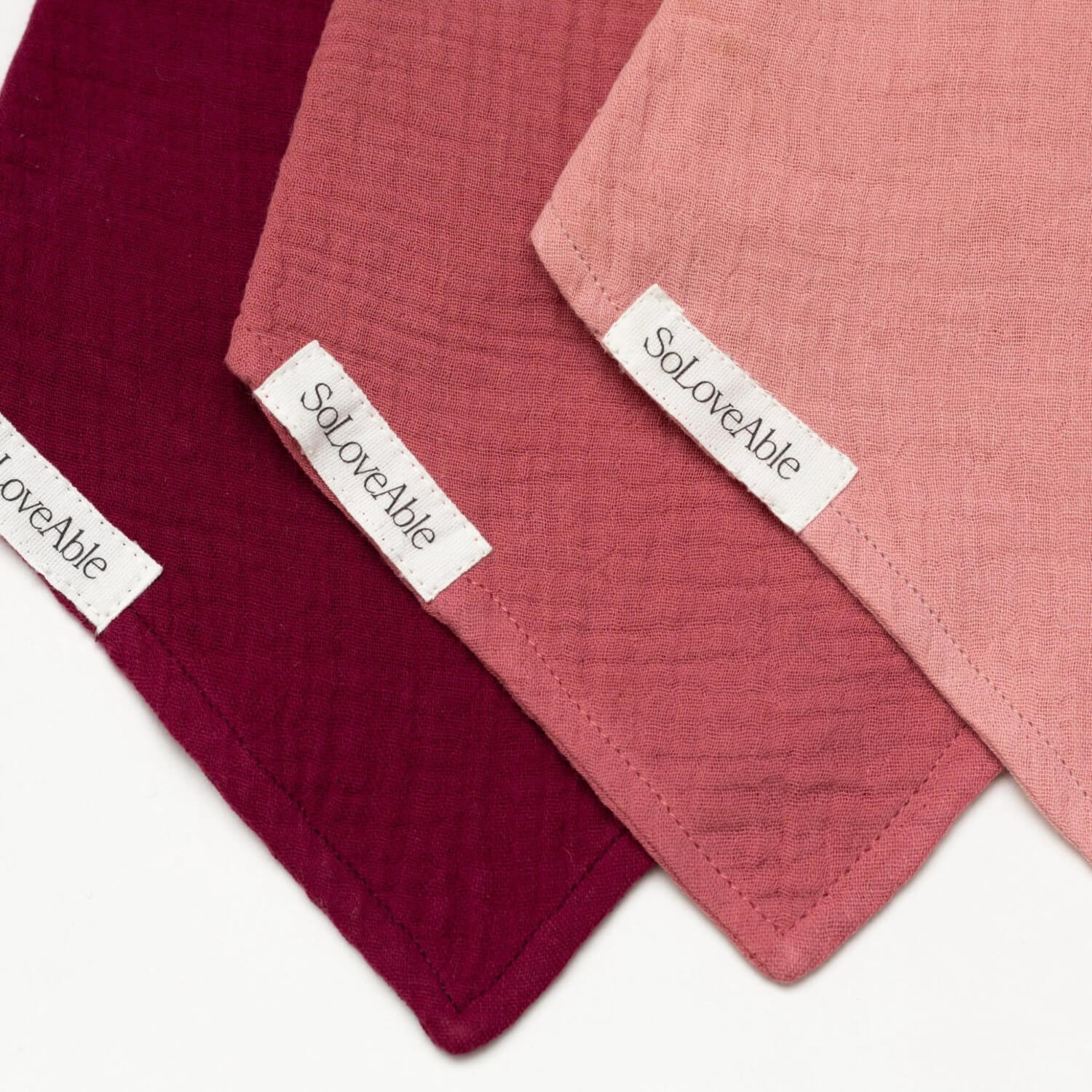 Soloveable close-up of muslin baby bandana bibs in pink, red and burgundy