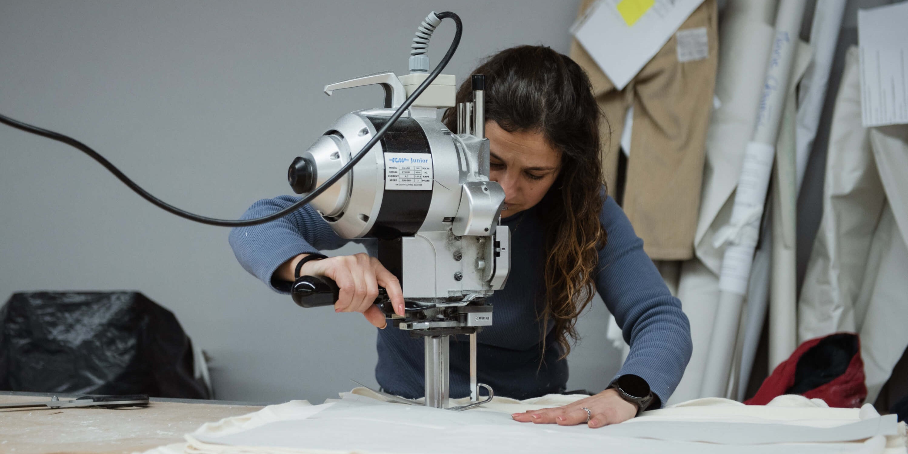 Woman cutting organic fabric in a sustainable GOTS-certified clothing workshop in Portugal.