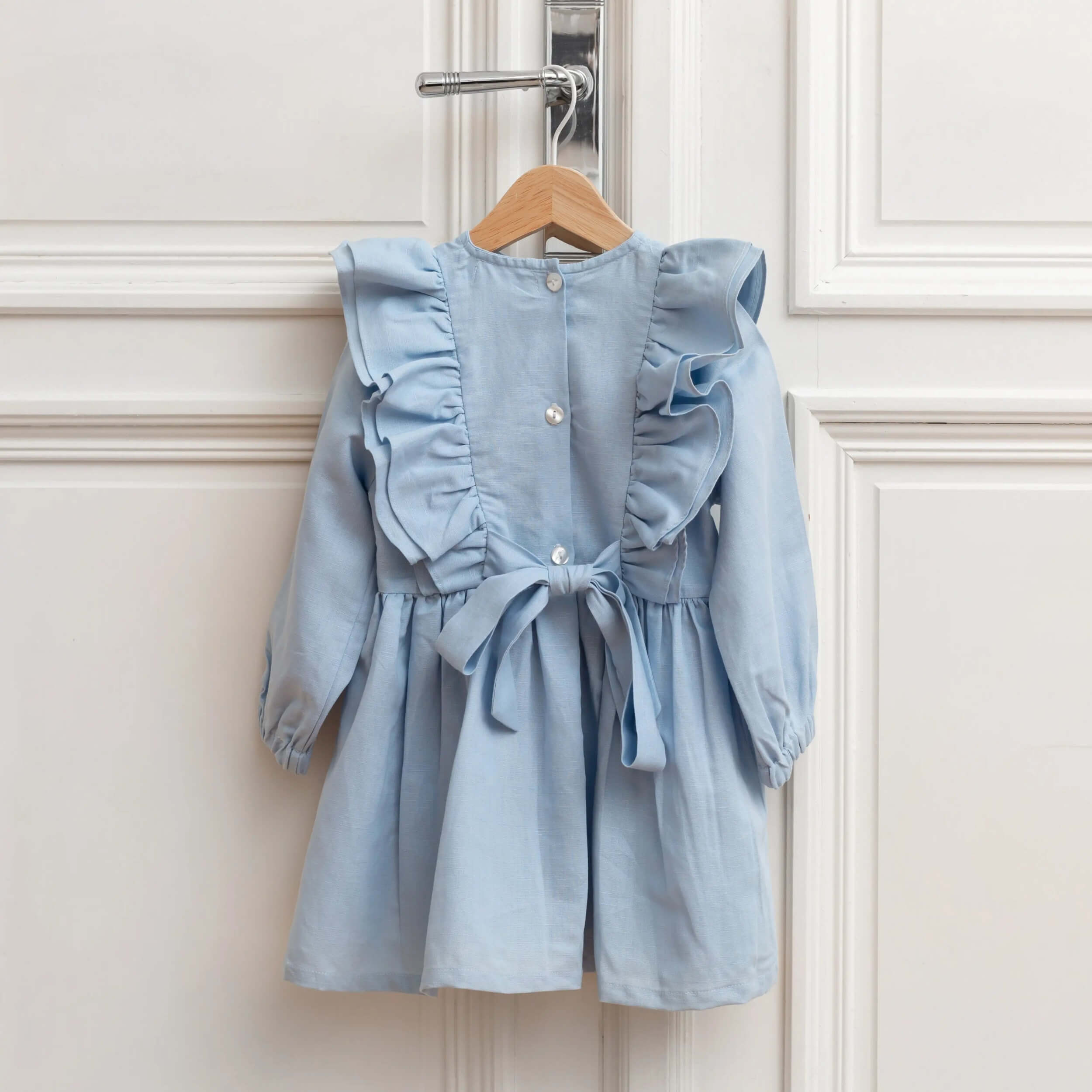 Back view of blue linen girls dress with bow tie and buttons, ruffle sleeves, timeless elegant children's outfit.