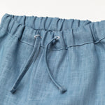 Close-up of the elastic waistband and drawstring on blue linen baby and toddler pants.