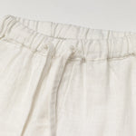 Close-up of the elastic waistband and drawstring on white linen baby and toddler pants.