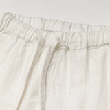 Close-up of the elastic waistband and drawstring on white linen baby and toddler pants.