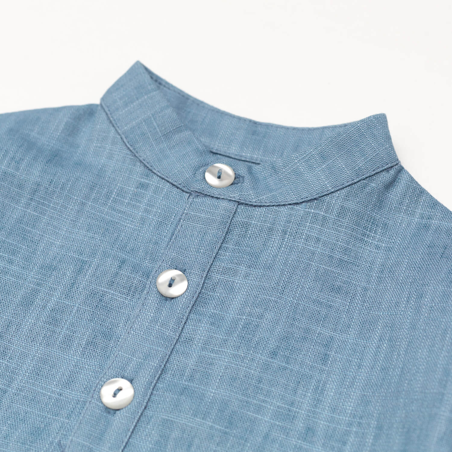 Close-up of the collarless neckline and button placket on the blue linen baby and toddler long-sleeve shirt.