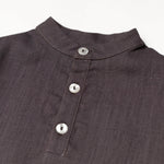 Close-up of the collarless neckline and button placket on the brown linen baby and toddler long-sleeve shirt.