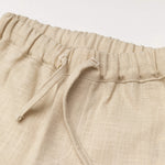 Close-up of the elastic waistband and drawstring on beige linen pants for babies and toddlers.