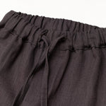 Close-up of the elastic waistband and drawstring on brown linen baby and toddler pants.