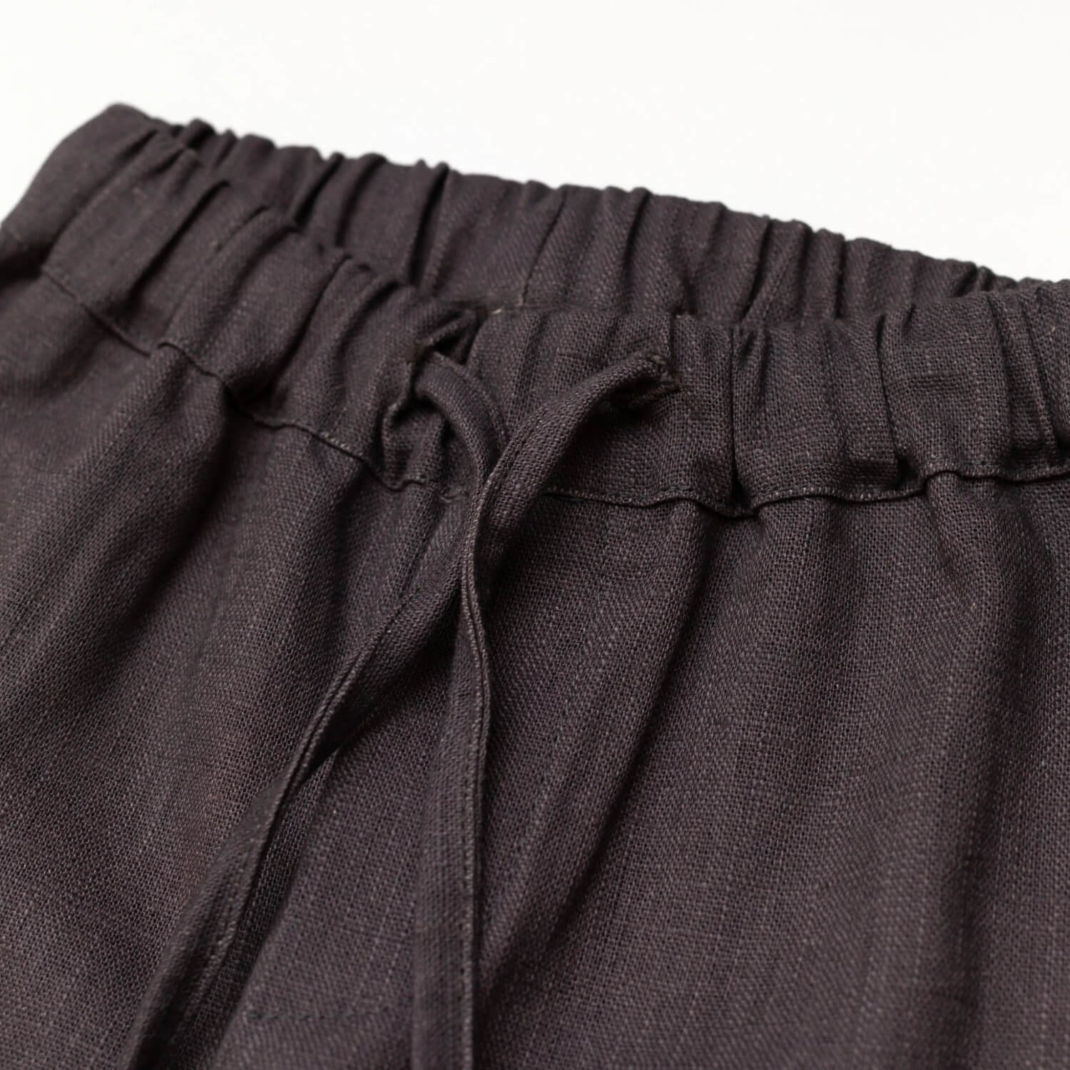 Close-up of the elastic waistband and drawstring on brown linen baby and toddler pants.