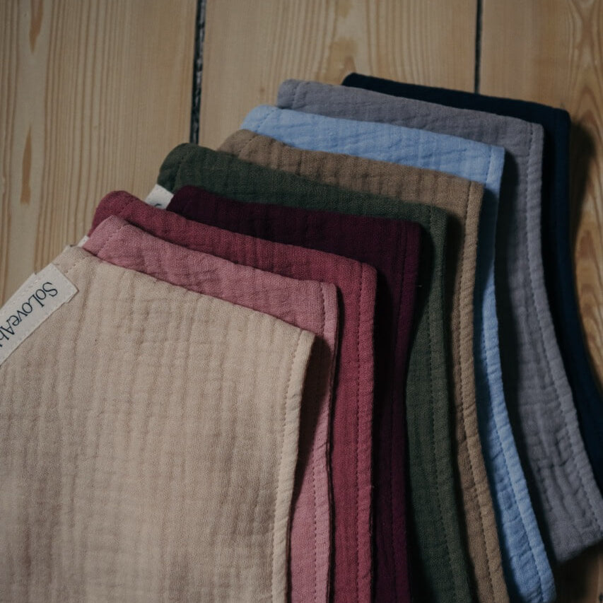 Breathable organic cotton baby clothes in multiple colors, made from moisture-wicking natural fabric by SoLoveAble.