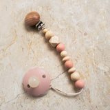 Pink silicone and natural wood pacifier clip with round and geometric beads.
