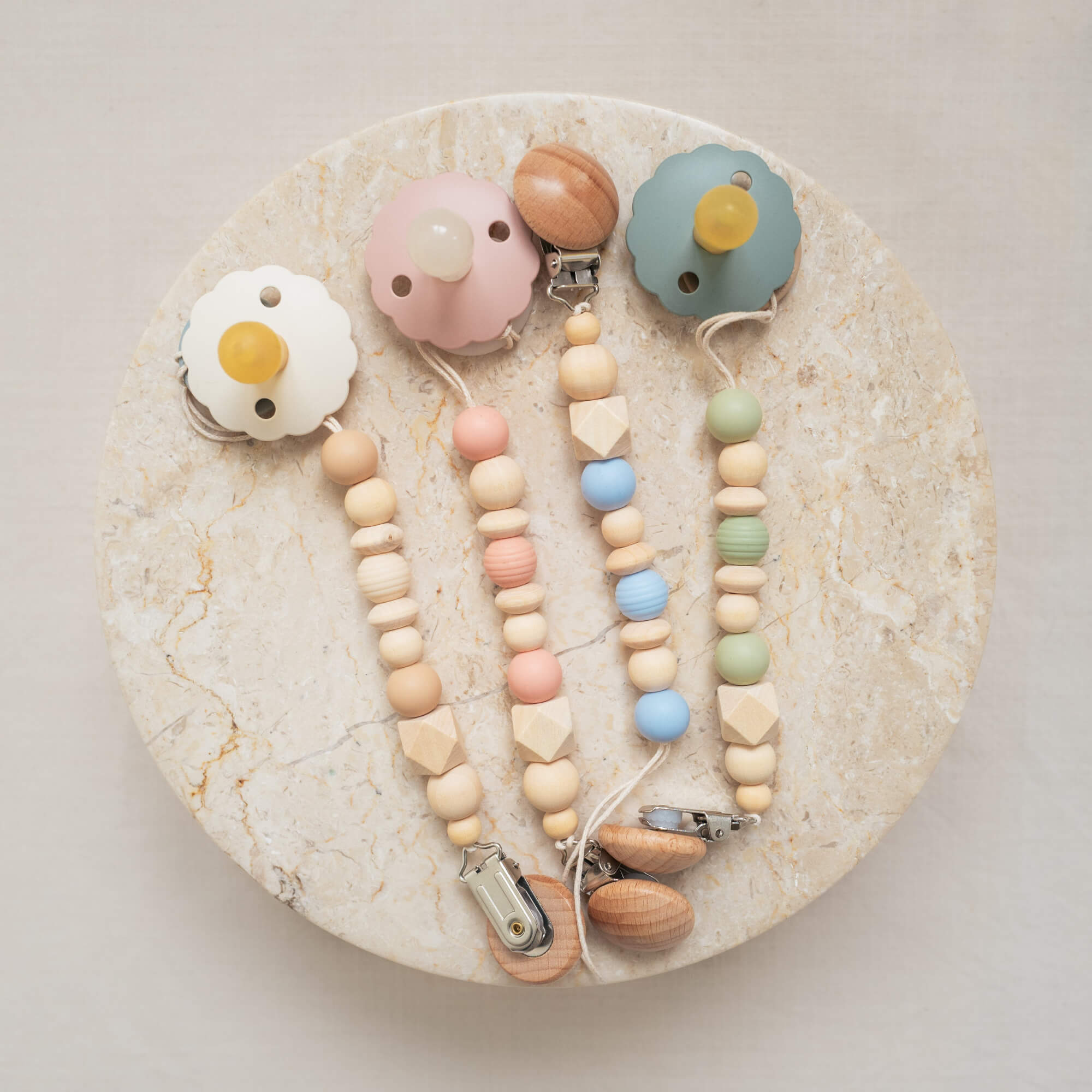 Pacifier clips made from silicone and natural wood beads in mixed pastel colors.