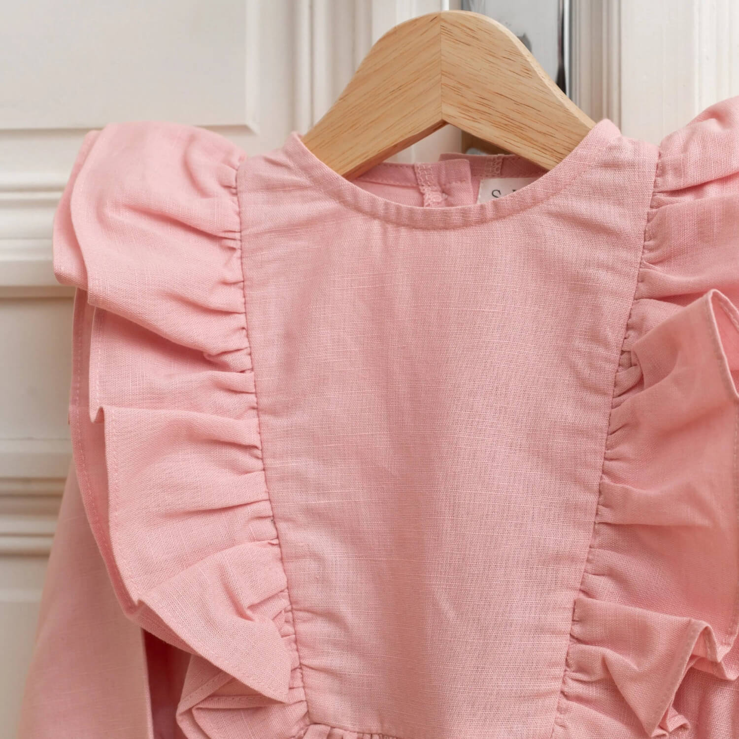 Close-up of pink linen kids linen dress with ruffle shoulder detail
