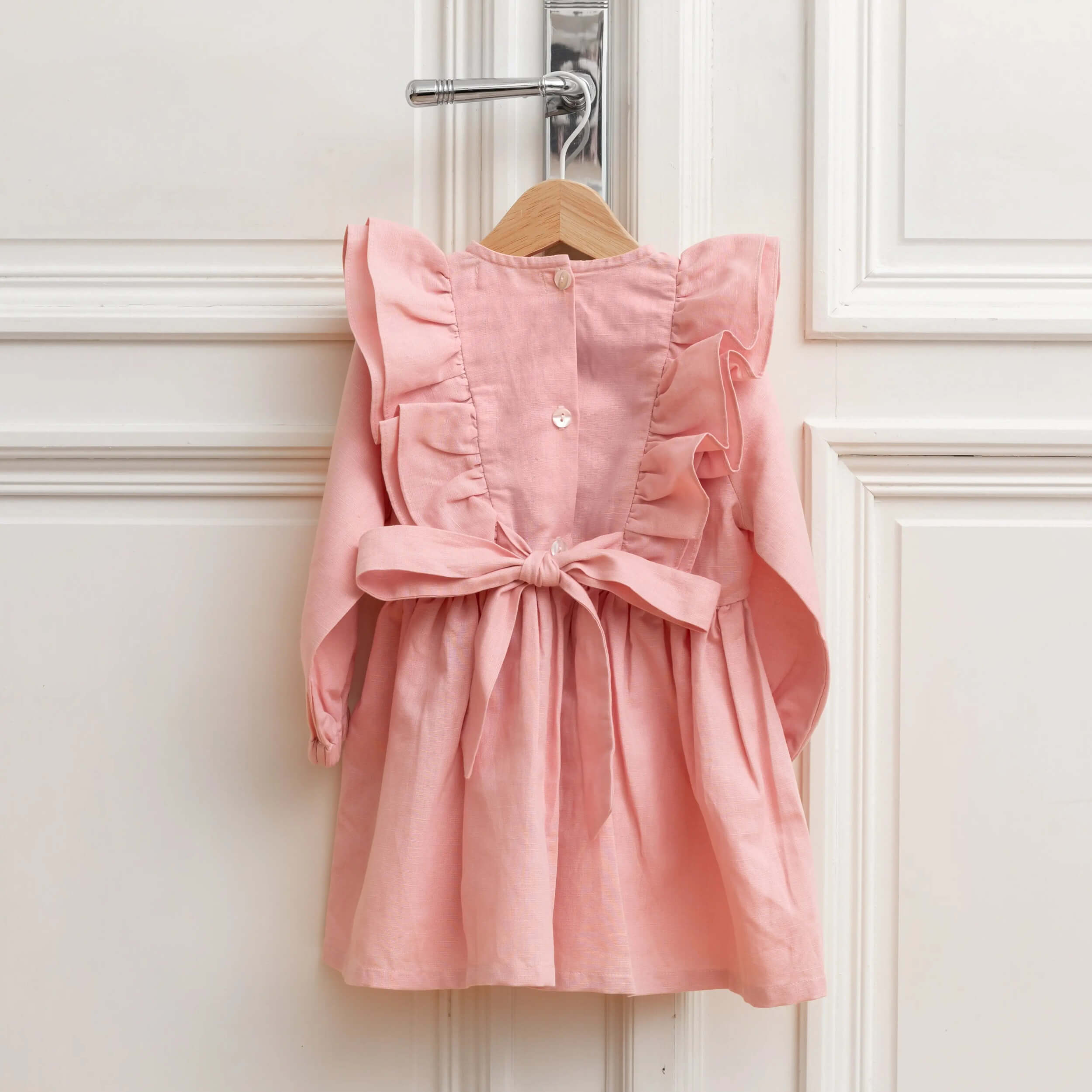Back view of pink linen girls dress with bow and ruffle details