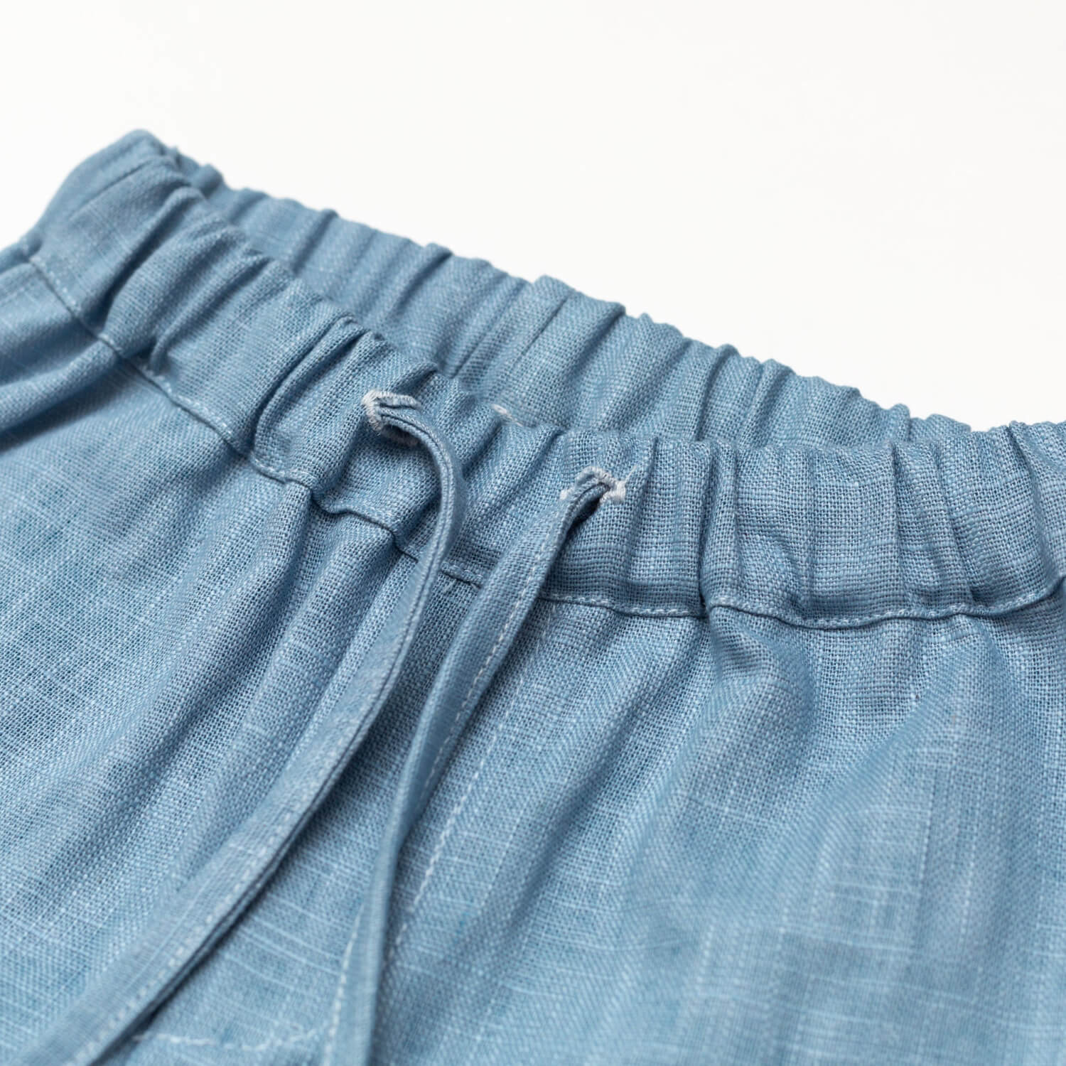 Close-up of the elastic waistband and drawstring on short blue linen pants for babies and toddlers.