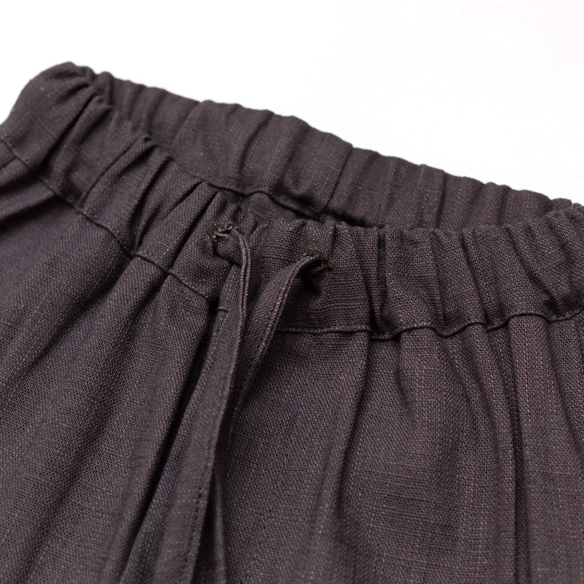 Close-up of the elastic waistband and drawstring on short brown linen pants for babies and toddlers.