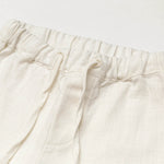 Close-up of the elastic waistband and drawstring on short white linen pants for babies and toddlers.