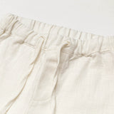 Close-up of the elastic waistband and drawstring on short white linen pants for babies and toddlers.