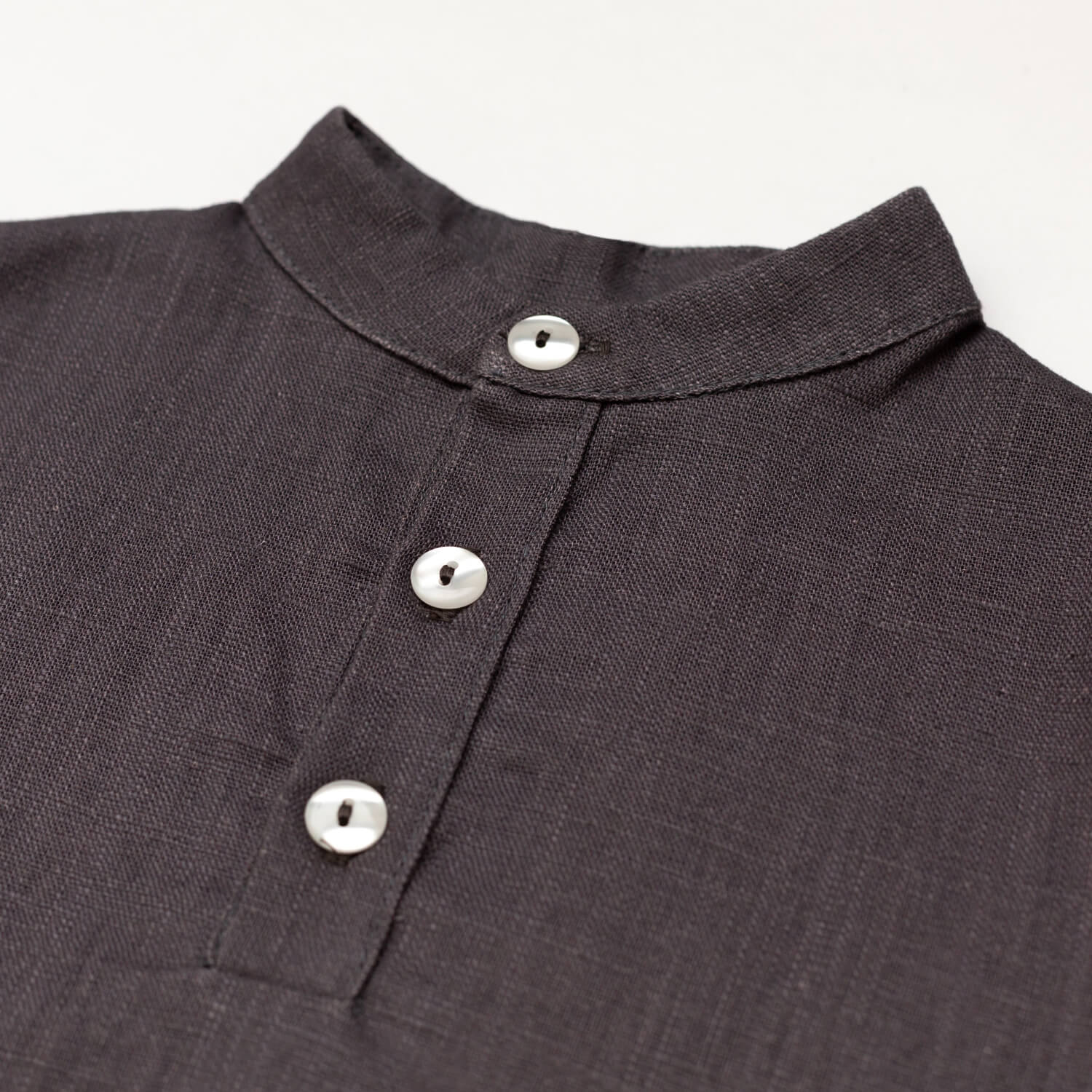 Close-up of the collar and buttons on a brown linen short-sleeve shirt for babies and toddlers.