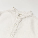 Close-up of the collar and buttons on a white linen short-sleeve shirt for babies and toddlers.