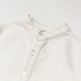 Close-up of the collar and buttons on a white linen short-sleeve shirt for babies and toddlers.