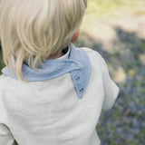 Soloveable grey muslin bandana bib on baby, with adjustable snap buttons and three size settings.