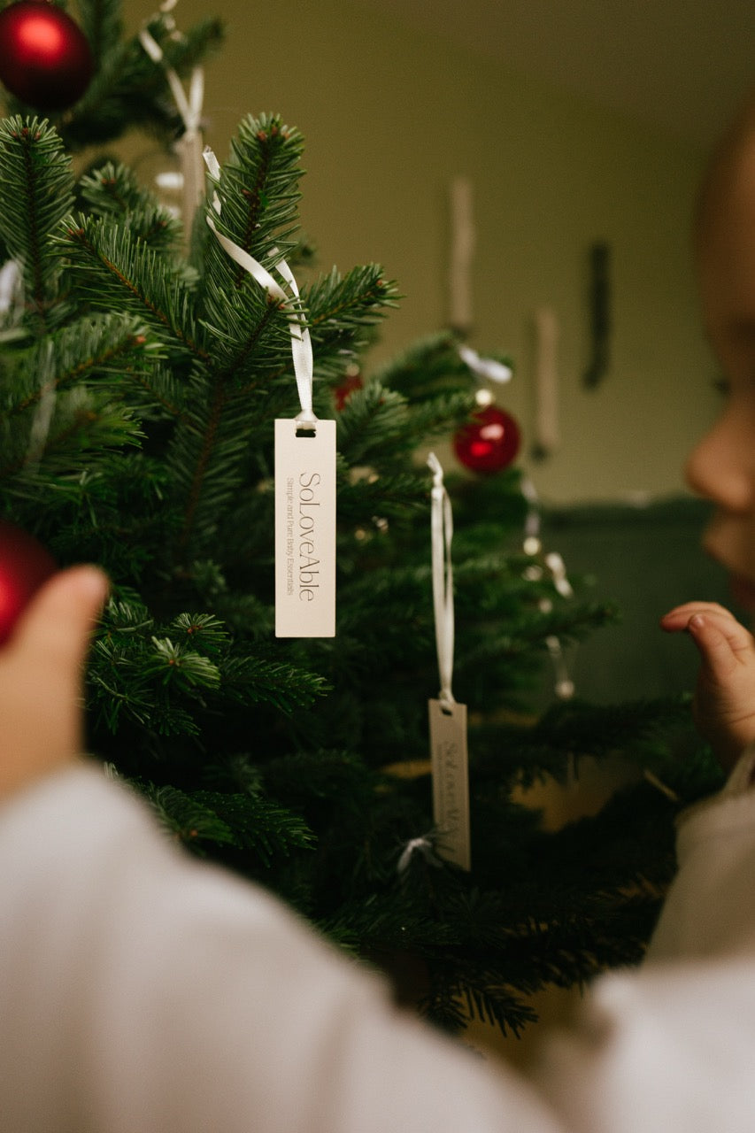 SoLoveAble brand tags hanging on a Christmas tree, representing sustainable baby and kidswear made from natural materials.