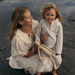 Mother and toddler wearing beige long linen outfits standing by the beach, showcasing the breathable long linen shirt for babies and kids.