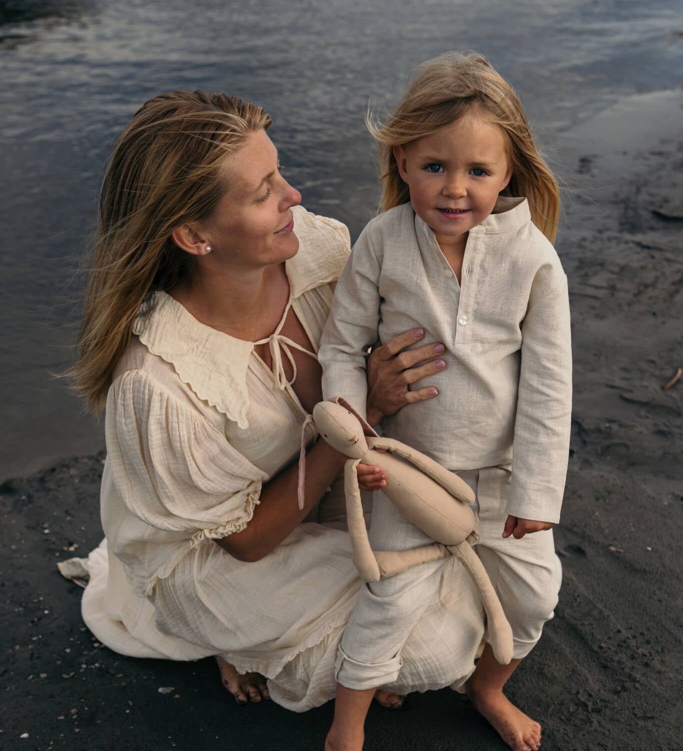 Mother and toddler wearing beige long linen outfits standing by the beach, showcasing the breathable long linen shirt for babies and kids.