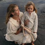 Mother and toddler wearing beige long linen outfits standing by the beach, showcasing the breathable long linen shirt for babies and kids.