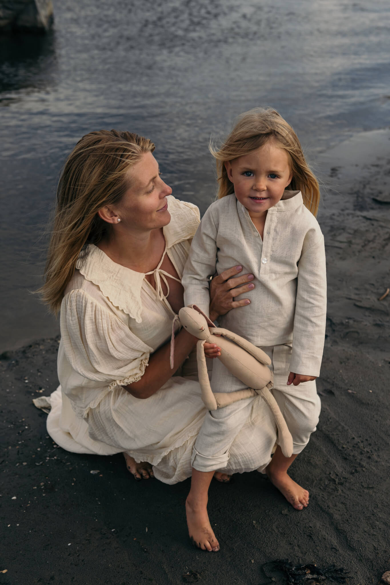 Mother and toddler wearing beige long linen outfits standing by the beach, showcasing the breathable long linen shirt for babies and kids.