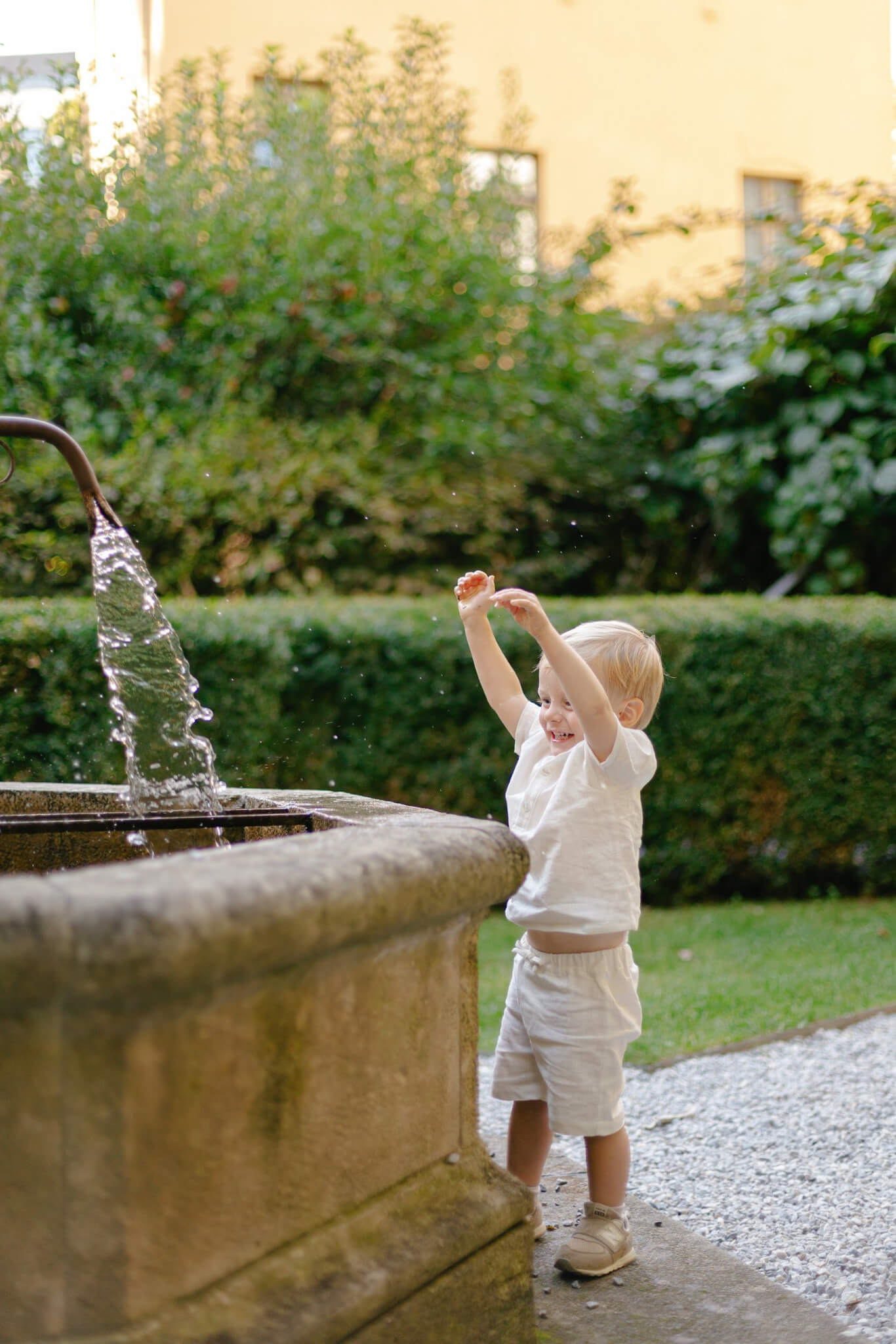 Toddler playing by a fountain wearing a soft natural linen outfit from SoLoveAble