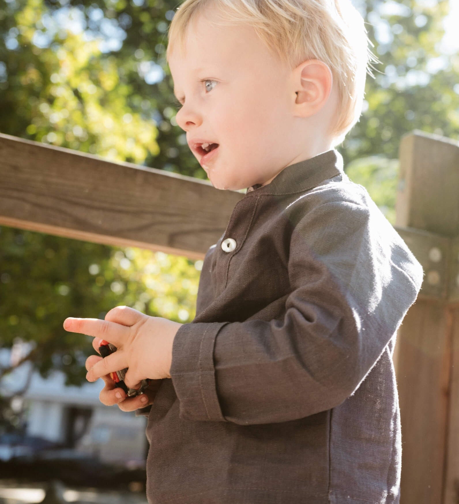 Toddler wearing a long-sleeve brown linen shirt outdoors.