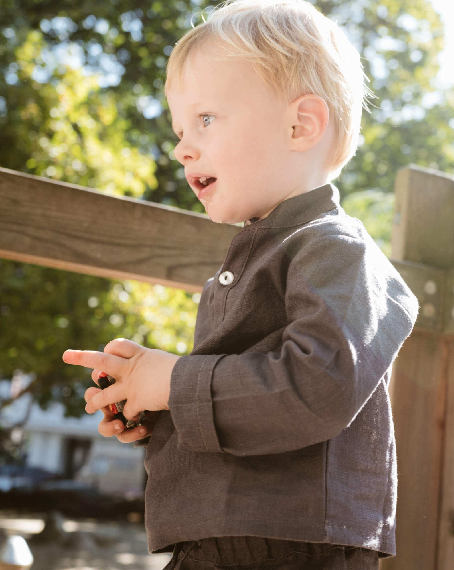 Toddler wearing a long-sleeve brown linen shirt outdoors.