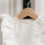 Close-up of white linen kids dress with soft ruffle details on hanger