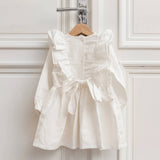 White linen baby dress hanging with button back and tie bow detail