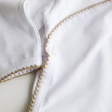 Close-up of caramel brown crochet trim on the white baby bodysuit.