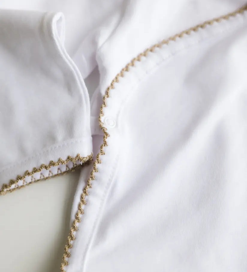 Close-up of caramel brown crochet trim on the white baby bodysuit.