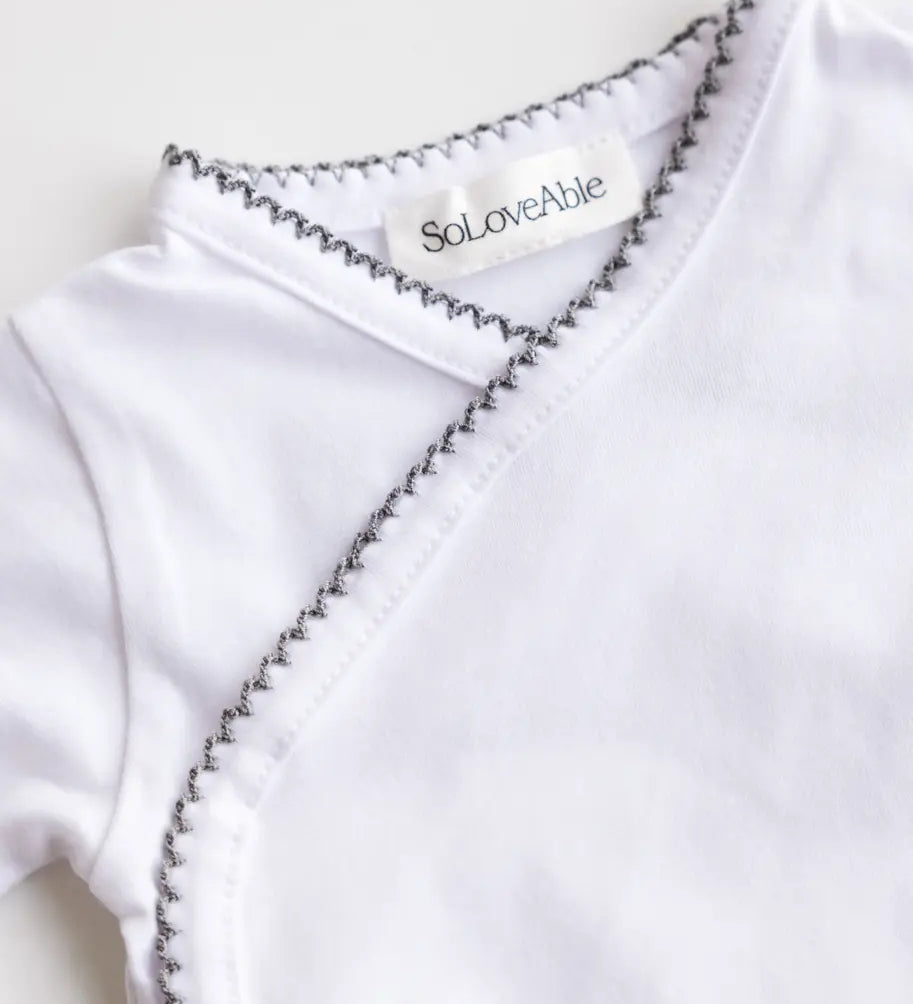 Close-up of heather grey crochet trim on the white baby bodysuit.