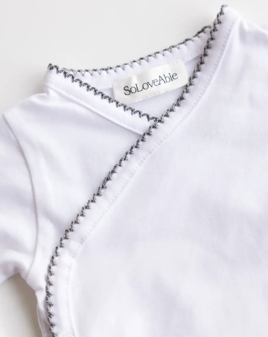 Close-up of heather grey crochet trim on the white baby bodysuit.