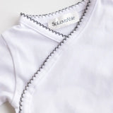 Close-up of heather grey crochet trim on the white baby bodysuit.