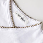 Close-up of sage green crochet trim on the white baby bodysuit.