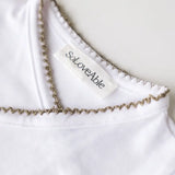 Close-up of sage green crochet trim on the white baby bodysuit.