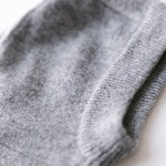 Close-up of heather grey cashmere knit balaclava showing soft texture and ribbed edge.