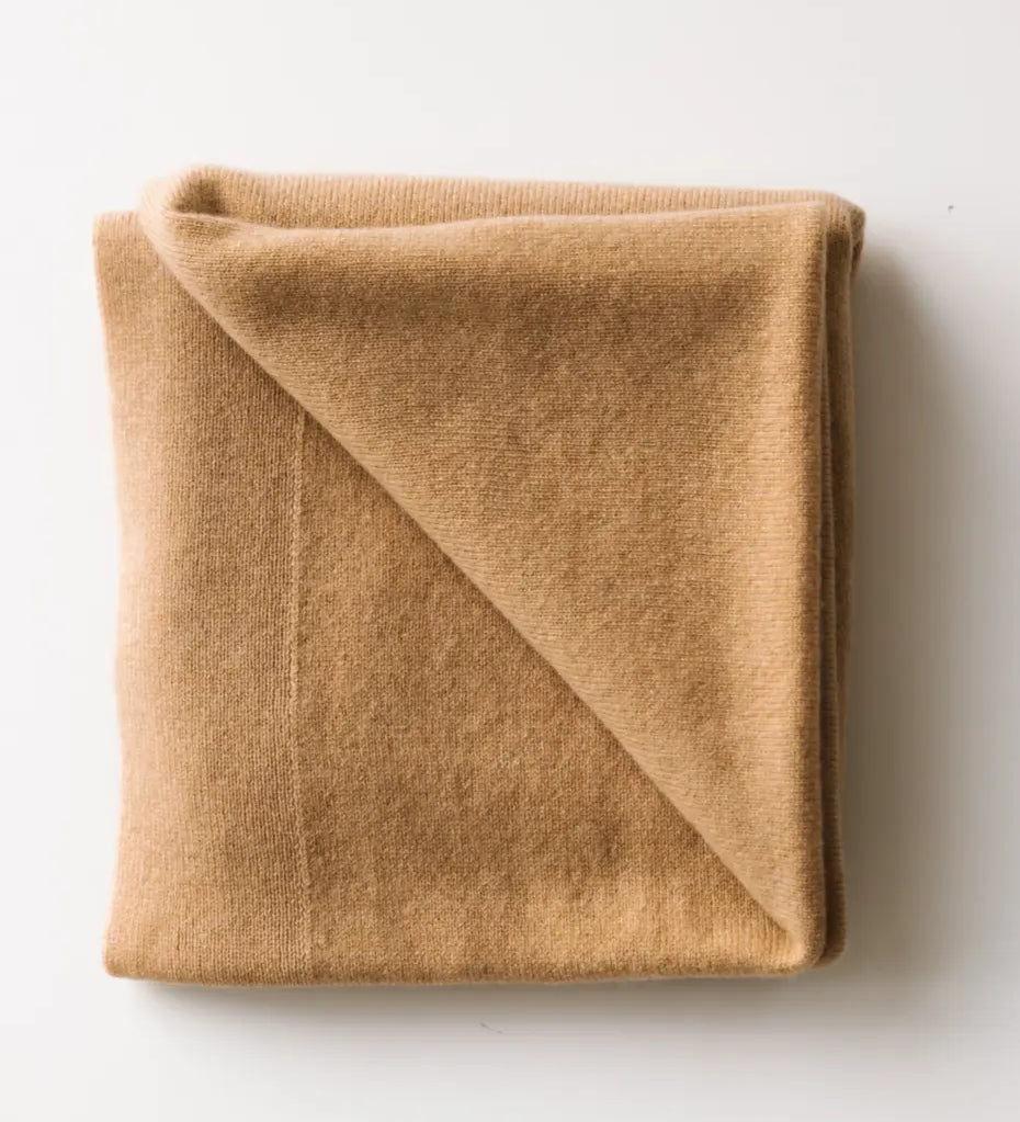 Caramel brown baby cashmere blanket neatly folded on a white surface.