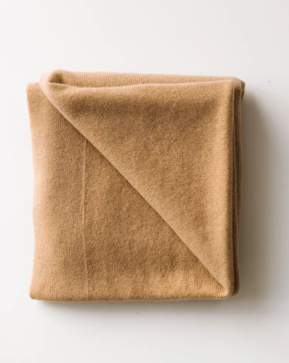 Caramel brown baby cashmere blanket neatly folded on a white surface.
