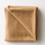 Caramel brown baby cashmere blanket neatly folded on a white surface.