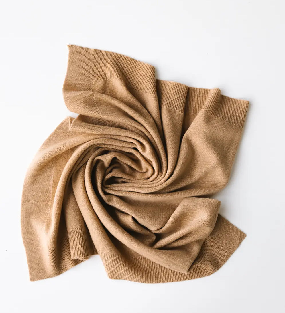 Baby cashmere blanket in caramel brown, softly draped and folded on a white background.
