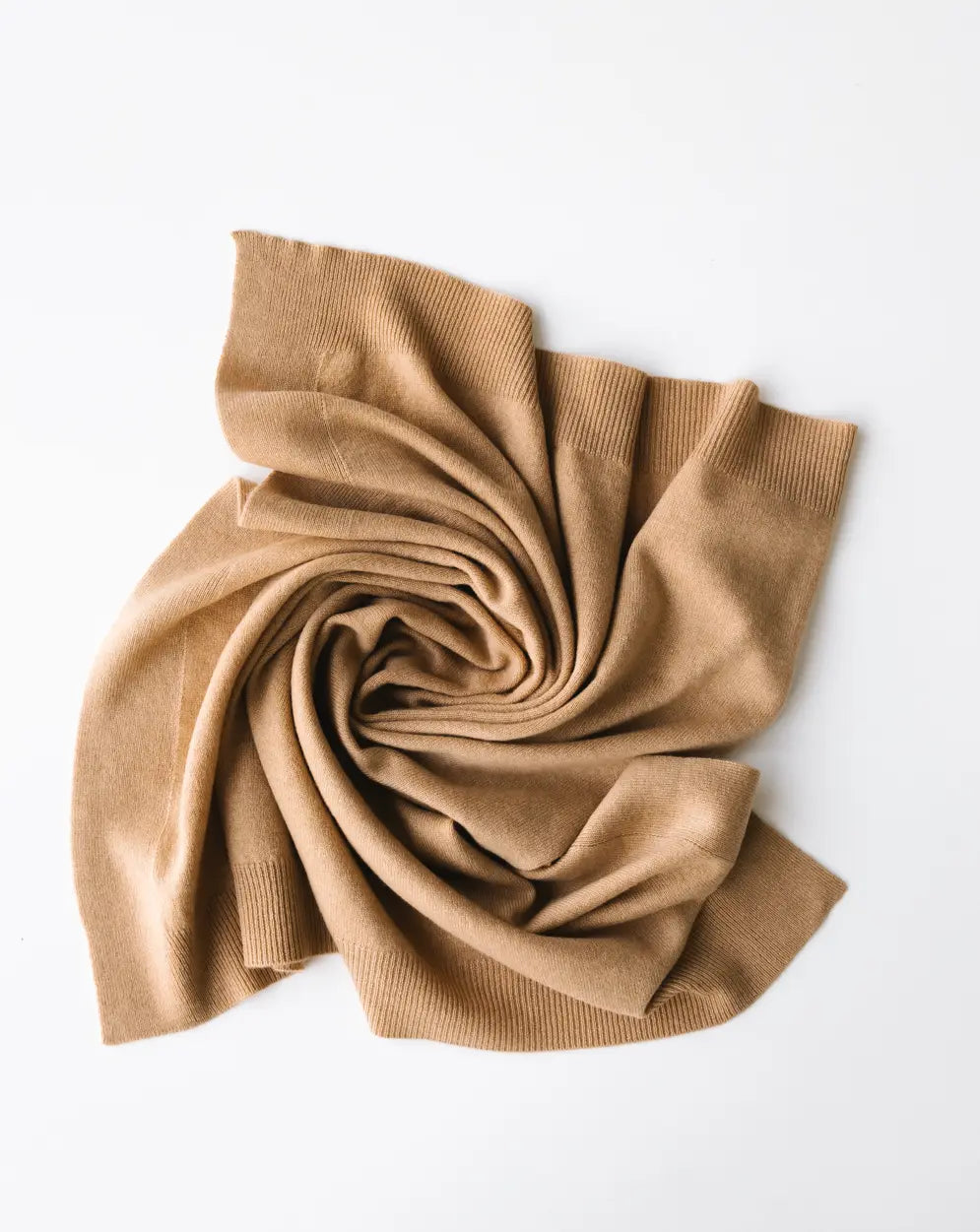 Baby cashmere blanket in caramel brown, softly draped and folded on a white background.