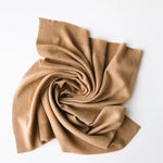 Baby cashmere blanket in caramel brown, softly draped and folded on a white background.